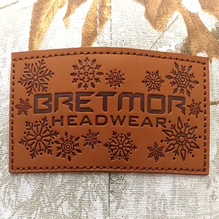 Photo of a rectangular real leather patch with a logo and holiday design debossed onto it