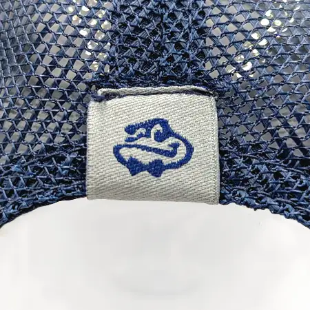 Photo of a woven loop label wrapped around and attached to the top of the back vent of a cap