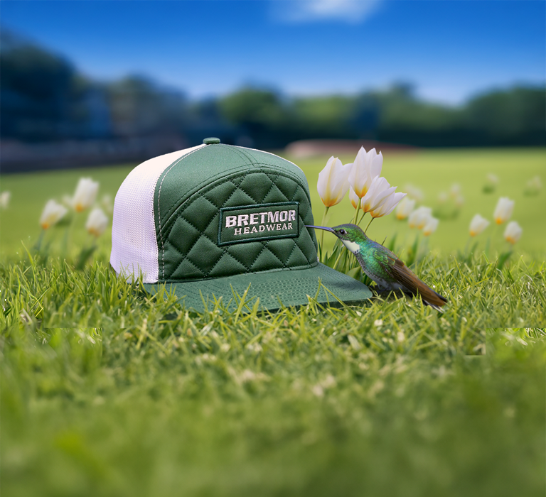 Background image of a cap with a leather patch on a post with hummingbirds hovering around it